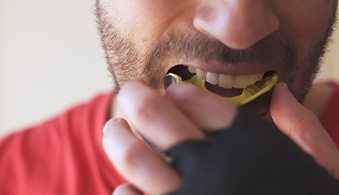 Closeup of man putting on mouthguard