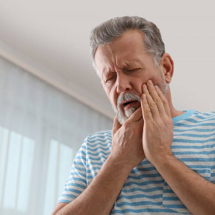 a man holding his cheek due to tooth pain