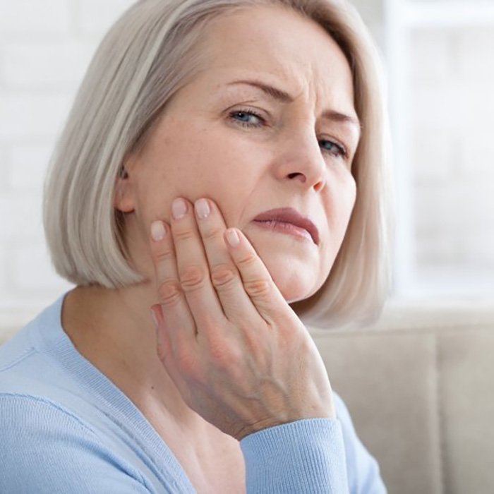 a woman holding her cheek due to tooth pain