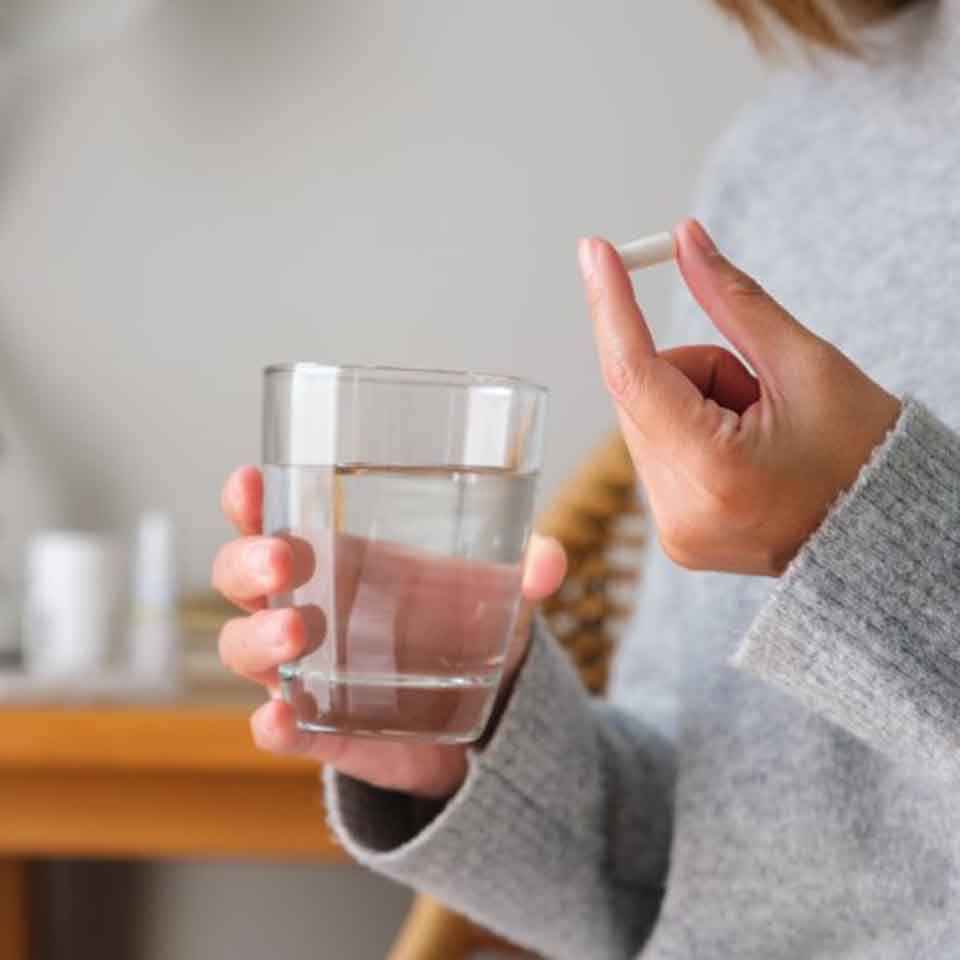 Lady holds pill and glass of water