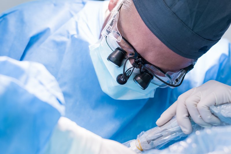 A closeup of a dentist removing a failed dental implant